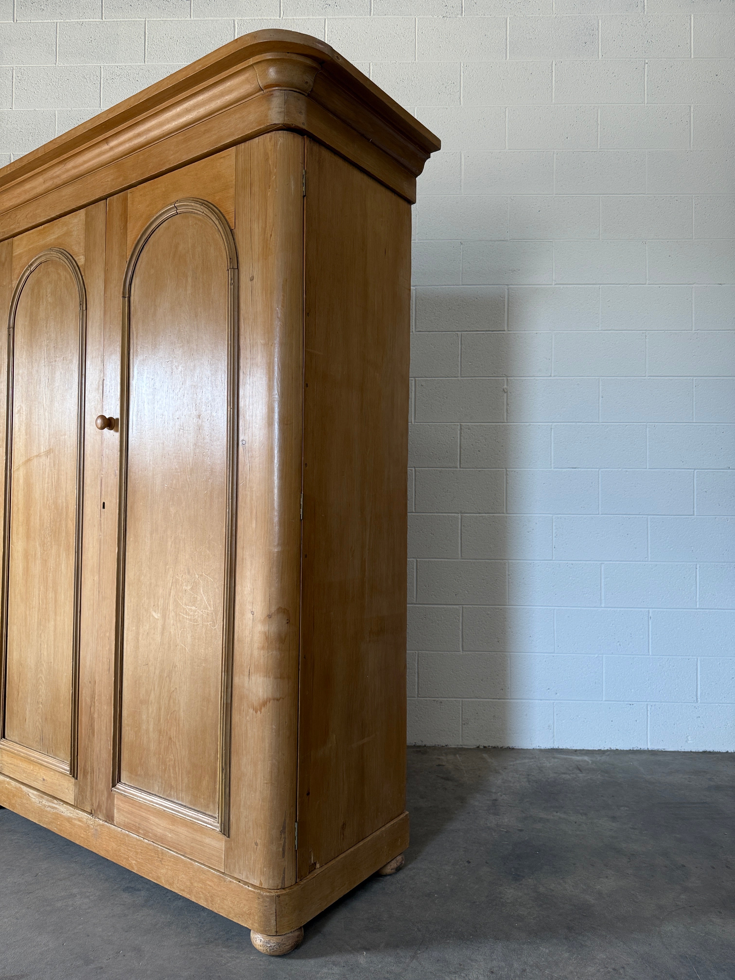 Antique English pine wardrobe with arched panel doors and fitted interior