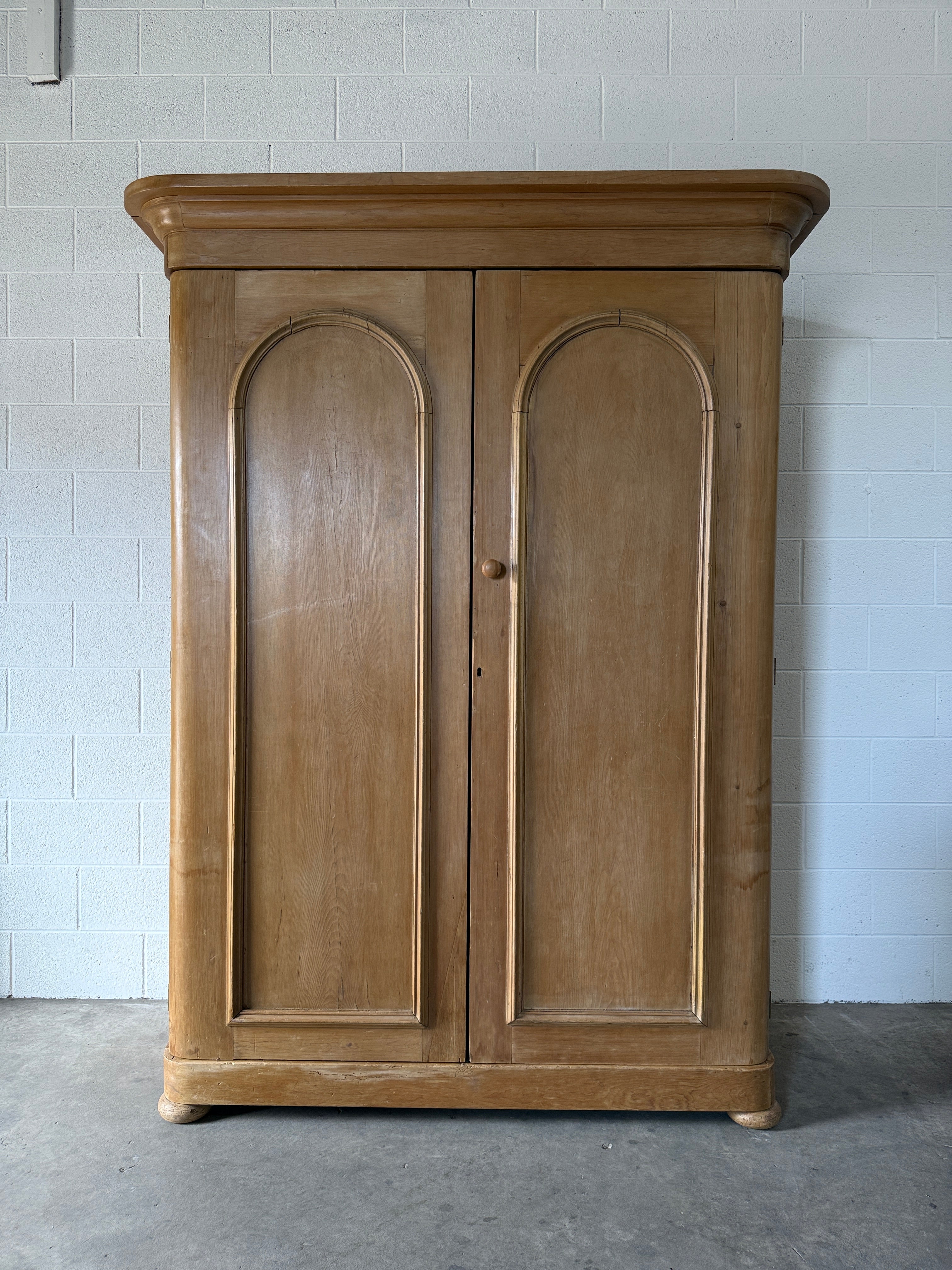 Antique English pine wardrobe with arched panel doors and fitted interior