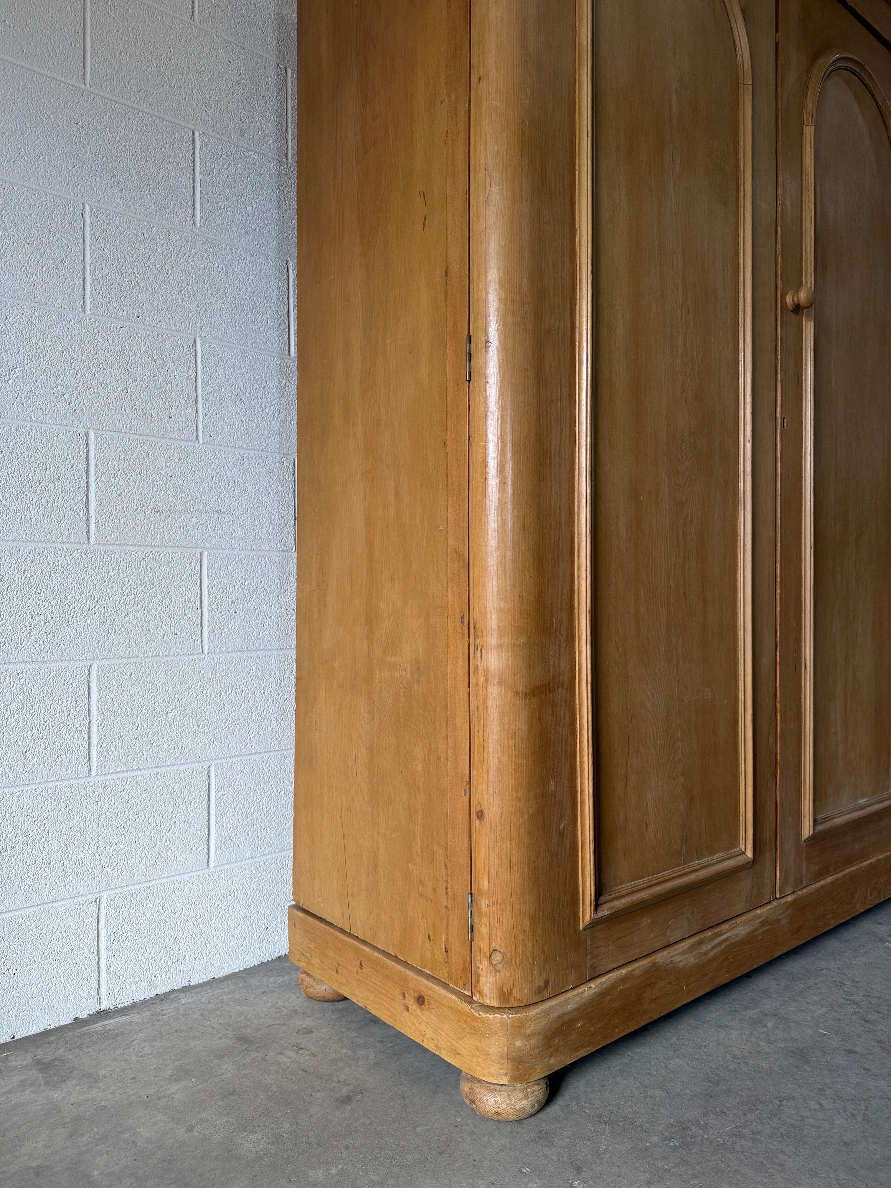 Antique English pine wardrobe with arched panel doors and fitted interior