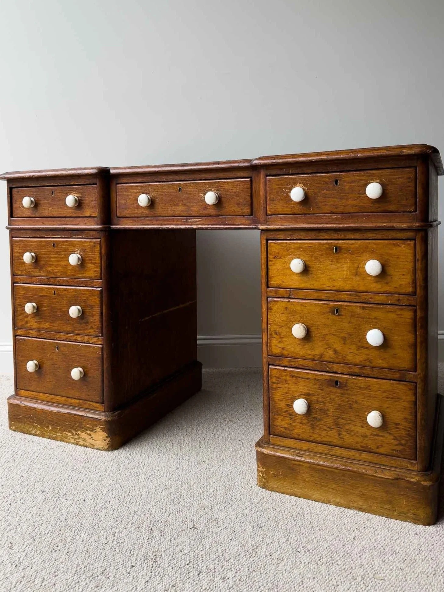 Dark waxed English antique pine desk with white knobs
