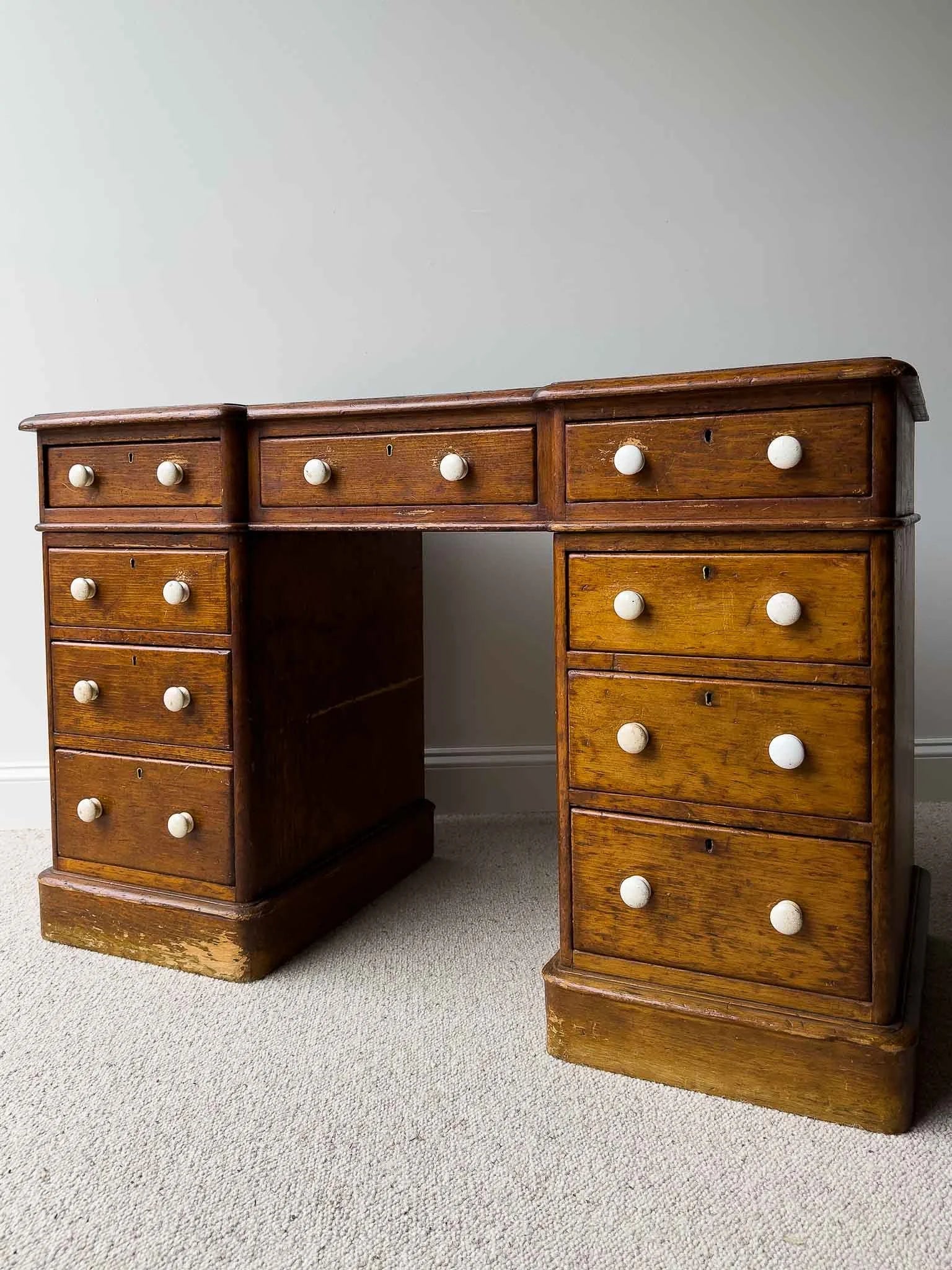 Dark waxed English antique pine desk with white knobs